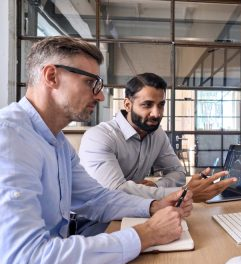 Two professionals discussing SpineLegal Software features on a laptop in a modern office setting.